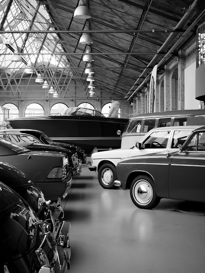 Monochrome photo of classic cars inside a Berlin exhibition hall, showcasing vintage automotive design.